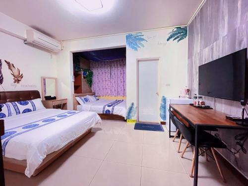 1 dormitorio con 2 camas, escritorio y TV en 親愛的民宿 en Jinning