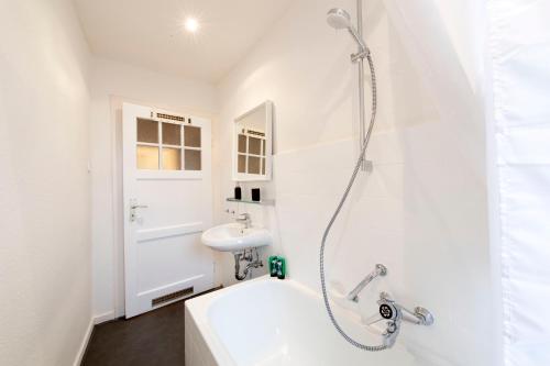 ein weißes Bad mit einer Dusche und einem Waschbecken in der Unterkunft Cozy Apartment ° 7 beds ° 3 bed rooms in Kleve