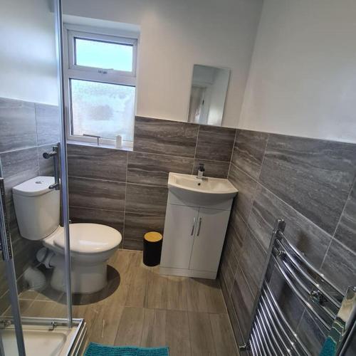 a bathroom with a toilet and a sink and a window at Lovely Home away from home! in Bexleyheath