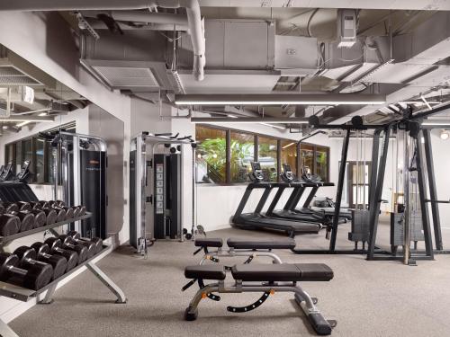 a gym with rows of treadmills and machines at Mayfair House Hotel & Garden in Miami