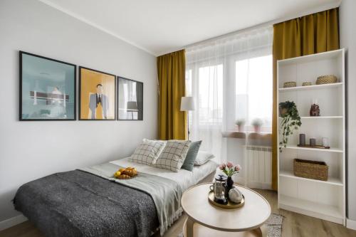 a white bedroom with a bed and a table at Apartments Centre by Arrenda in Warsaw