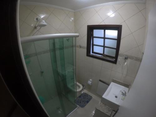 a bathroom with a shower and a toilet and a window at Chalé Recanto do Barão in Boicucanga