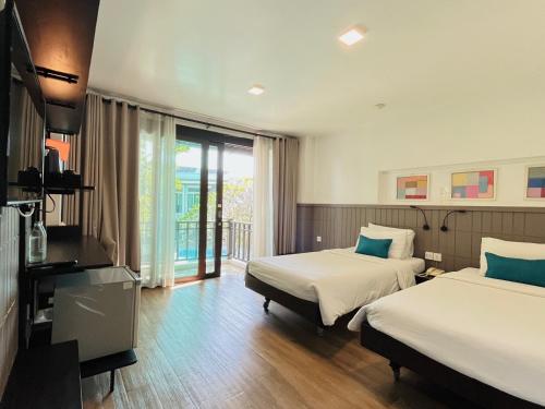 a hotel room with two beds and a balcony at The Mantrini Chiang Rai in Chiang Rai