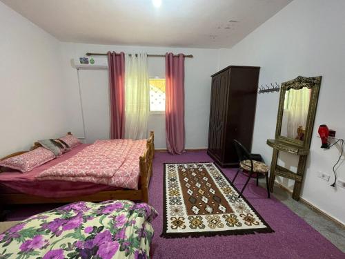 a bedroom with two beds and a mirror and purple carpet at Its your choice hostel in Wadi Musa