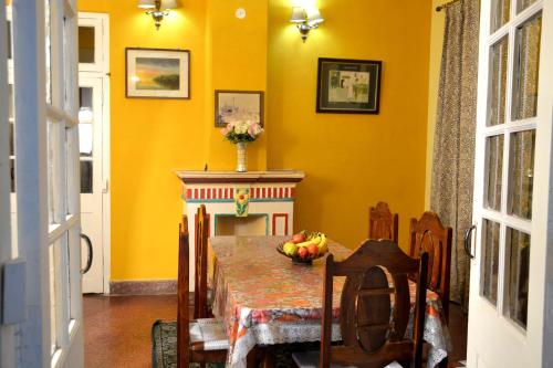 a dining room with a table and a yellow wall at Solan Retreat in Solan