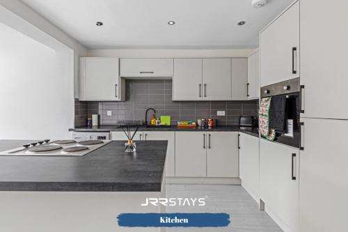 a kitchen with white cabinets and a black counter top at Tipton 3 Bedroom House Garden Sleeps 7 - JRR Stays in Coseley