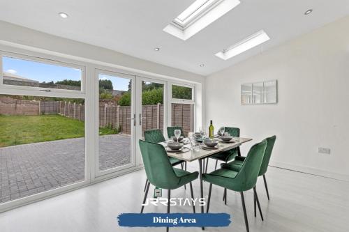 a dining room with a table and green chairs at Tipton 3 Bedroom House Garden Sleeps 7 - JRR Stays in Coseley