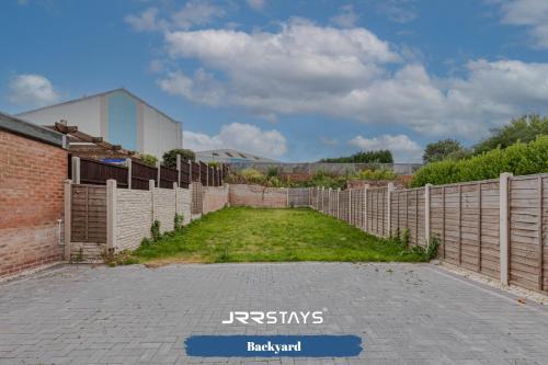 einen Zaun in einem Hof neben einem Backsteingebäude in der Unterkunft Tipton 3 Bedroom House Garden Sleeps 7 - JRR Stays in Coseley