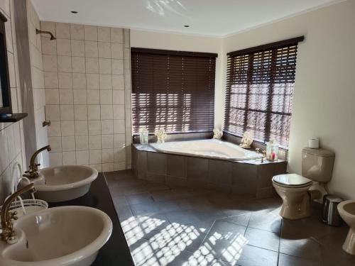 a bathroom with two sinks and a tub and a toilet at Beynespoort Farm in Cullinan