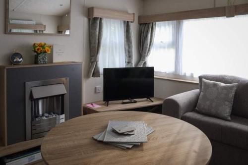 a living room with a table and a tv at Bimble Lodge in Langport