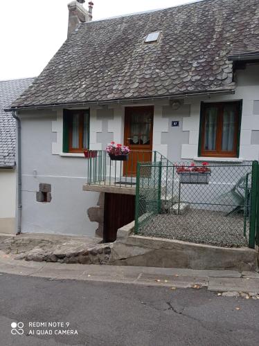 een wit huis met een veranda met bloemen erop bij Agréable T2 avec petite cour privative in La Bourboule