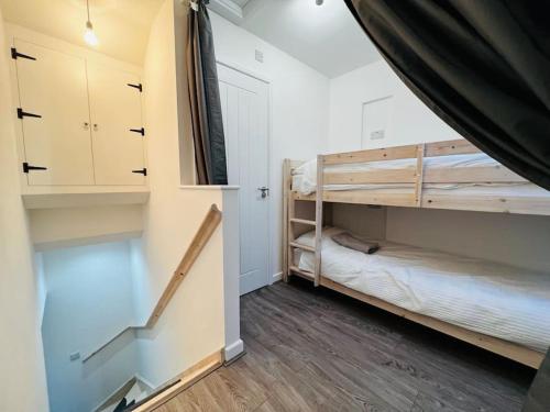 a room with two bunk beds and a staircase at Barn Cottage, with pre booked use of Indoor Swimming Pool in Frome