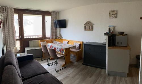 Il comprend un salon avec une table et une cuisine avec un canapé. dans l'établissement Le Cocon Themnest, à La Mongie