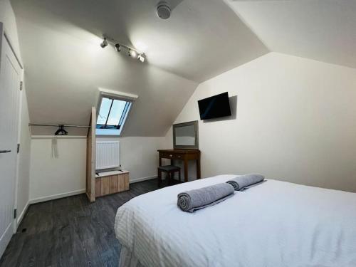 a bedroom with a large white bed and a television at Barn Cottage in Frome