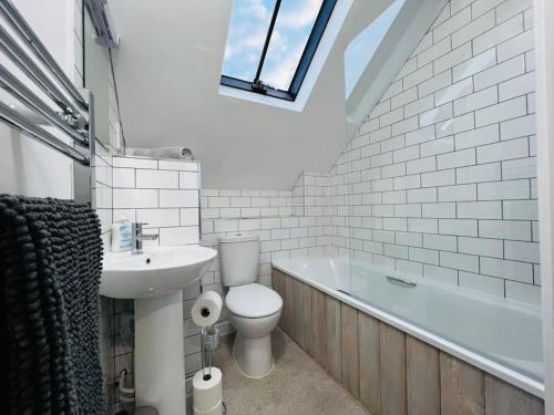 a bathroom with a toilet and a sink and a bath tub at Barn Cottage in Frome