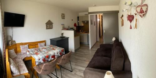 een woonkamer met een bank en een tafel en een keuken bij Le Cocon Themnest in La Mongie