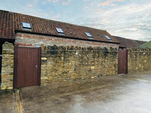 a brick building with two doors and a fence at Barn Cottage, with pre booked use of Indoor Swimming Pool in Frome