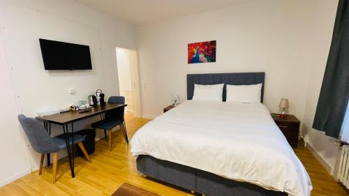 ein Schlafzimmer mit einem großen Bett und einem Schreibtisch mit einem Computer in der Unterkunft Akomo Bern in Bern