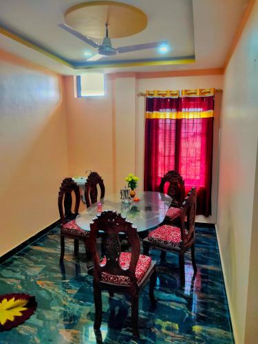 Un comedor con una mesa de cristal y sillas. en Tathāgata Homestay, en Rummindei