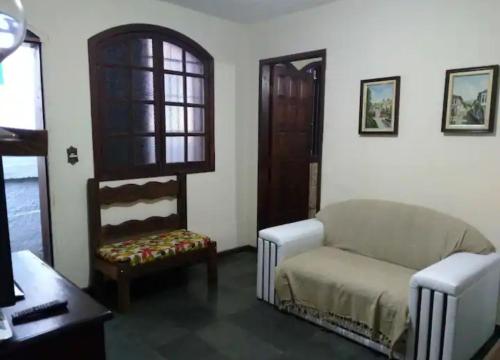 uma sala de estar com um sofá e uma cadeira em Imperdível - Casa aconchegante com varanda em Ouro Preto