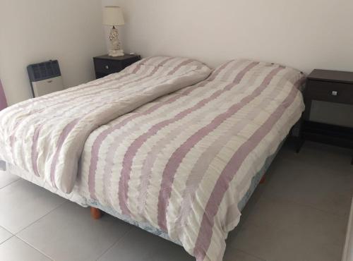 a bed with a striped comforter in a bedroom at Wenuray MdQ in Mar del Plata
