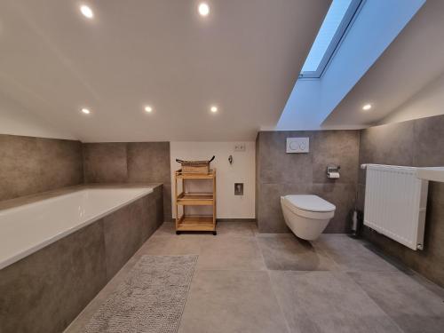een badkamer met een bad, een toilet en een dakraam bij Zollhaus 65 in Reit im Winkl