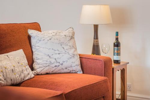 a pillow on a chair next to a lamp and a bottle of wine at farmhouse cottage in Keswick