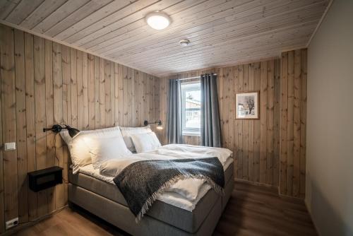 ein Schlafzimmer mit einem Bett mit einer Holzwand in der Unterkunft Bjorli Fjellstuer - by Classic Norway Hotels in Bjorli