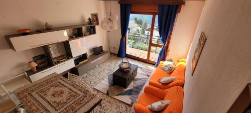 sala de estar con sofá naranja y chimenea en Bellavista - Residence in Barzio center near free ski shuttle, en Barzio