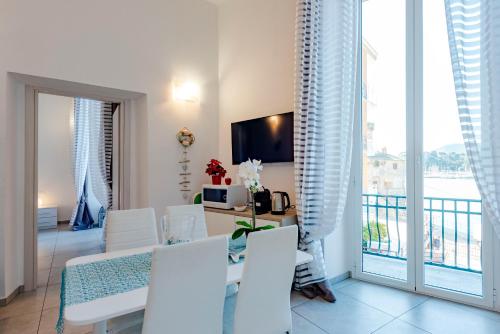 a living room with a table and chairs and a balcony at Alla Casa Rosa al Mare, Central Seafront Stay, Air Conditioning, Wi-Fi, the Ideal Choice for a Relaxing and Exciting Coastal Escape, with available on request at 20,00 euro per night Private Garage, Welcome kit Priority, Prosecco and Canestrelli in Rapallo
