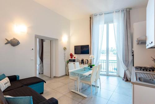 a kitchen and a living room with a table and a couch at Alla Casa Rosa al Mare, Central Seafront Stay, Air Conditioning, Wi-Fi, the Ideal Choice for a Relaxing and Exciting Coastal Escape, with available on request at 20,00 euro per night Private Garage, Welcome kit Priority, Prosecco and Canestrelli in Rapallo
