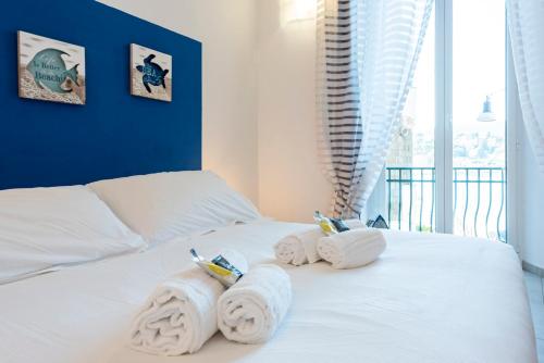 a bedroom with white towels on a bed at Alla Casa Rosa al Mare, Central Seafront Stay, Air Conditioning, Wi-Fi, the Ideal Choice for a Relaxing and Exciting Coastal Escape, with available on request at 20,00 euro per night Private Garage, Welcome kit Priority, Prosecco and Canestrelli in Rapallo