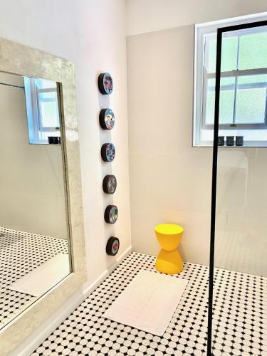 a bathroom with a shower and a yellow stool at 1 Royal Street Guesthouse in Riebeek-Kasteel
