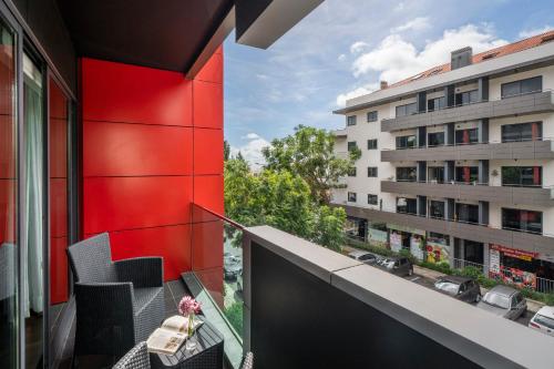 uma varanda com cadeiras e uma parede vermelha e um edifício em Madalenas XXI by An Island Apart no Funchal