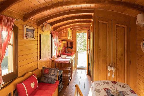una piccola camera ferroviaria con un divano rosso e un tavolo di Roulotte Ancolie a Gèdre
