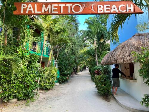 a man standing outside of a plantation beach sign at Laura's Lookout in Caye Caulker