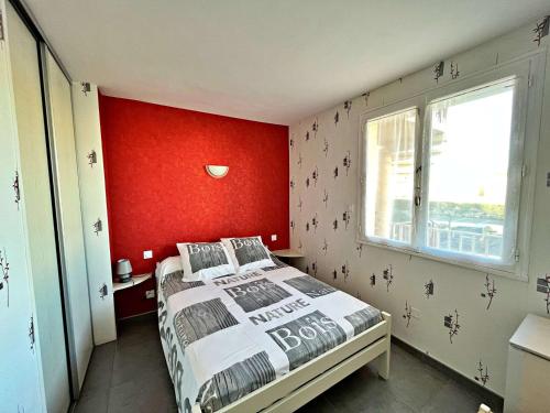 une chambre avec un lit et un mur rouge dans l'établissement Appartement au centre de Marseillan avec terrasse et parking, proche commodités - FR-1-387-178, à Marseillan