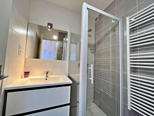 une salle de bain blanche avec un lavabo et une douche dans l'établissement Appartement au centre de Marseillan avec terrasse et parking, proche commodités - FR-1-387-178, à Marseillan