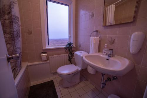 łazienka z umywalką, toaletą i oknem w obiekcie Snæfellsjökull Apartments w mieście Snæfellsbær