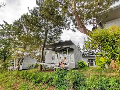 two people sitting on the porch of a tiny house at 153 Mountain View in Ban Huai Phai