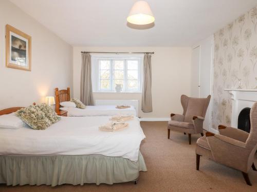 a bedroom with two beds and a chair at Twelve Oaks Farmhouse in Newton Abbot
