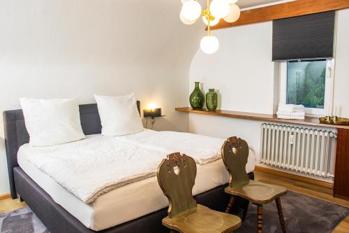 um quarto com uma cama com 2 cadeiras e uma janela em BlackNCozy - Großzügiges Designappartement mit Boxspringbetten und Heimkino em Feldberg