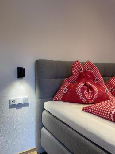 a bed with red pillows on a couch with a light at Schneiderhof in Weerberg