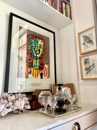 a table with glasses and a painting on a wall at 1 Royal Street Guesthouse in Riebeek-Kasteel