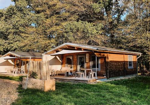 a log cabin with tables and chairs in the grass at destinature Dorf Südeifel in Ernzen