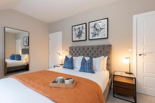 een slaapkamer met een groot bed met blauwe kussens bij Elliot Oliver - Stylish Loft Style Two Bedroom Apartment With Parking in Gloucester