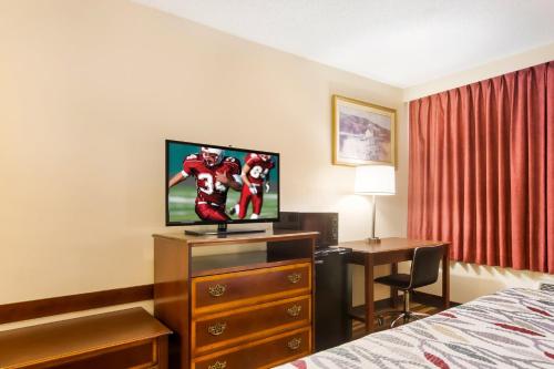 a hotel room with a bed and a tv and a desk at Red Roof Winchester - Lexington East in Winchester