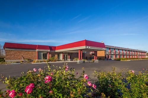 a building with a red roof with flowers in the foreground at Red Roof Winchester - Lexington East in Winchester
