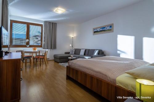a bedroom with a bed and a table and a couch at Apartmány Villa Severka in Vysoke Tatry - Novy Smokovec