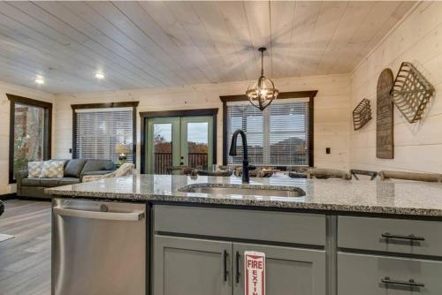 a kitchen with a sink and a living room at Blue Moon Ridge: Brand NEW Cabin! 5 bedrooms, pool/hot tub, theatre in Pigeon Forge